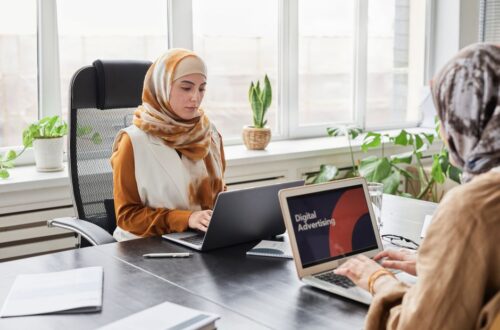 Een recruiter die een personeelsadvertentie schrijft op een laptop in een moderne kantooromgeving.